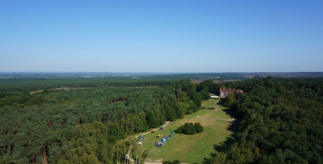 Aerial image shot on a drone of Avon Tyrrell's manor house in the New Forest - the manor house sits on a large forest site with trees and grass areas surronding it with tents out for campers