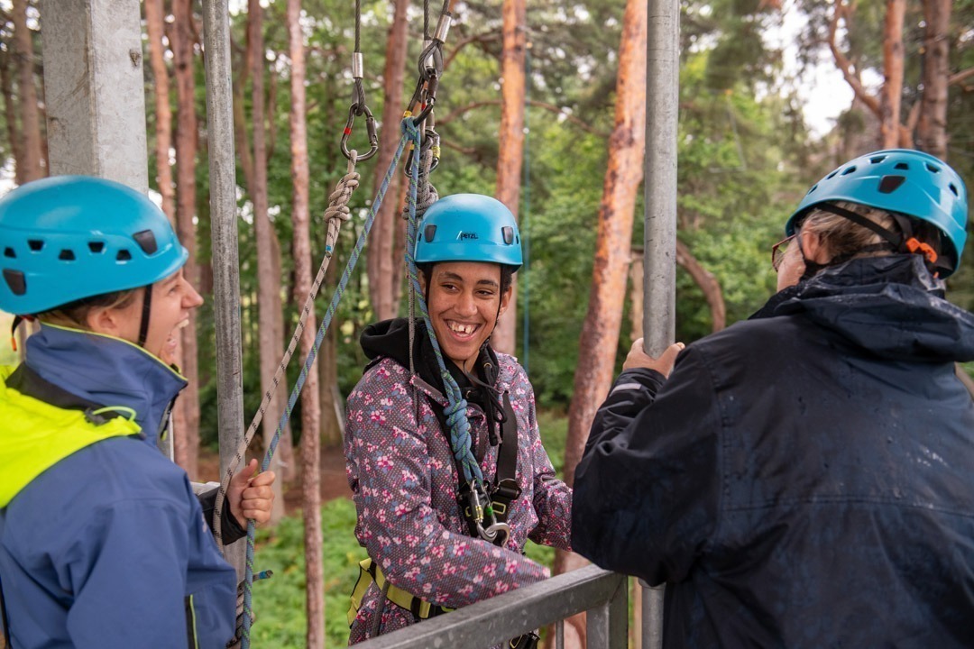 Young adult smiling to camera wearing blue helmet and purple coat