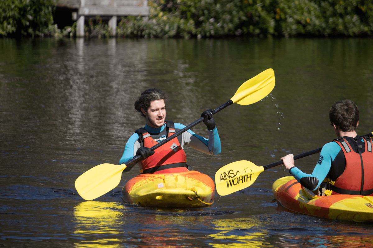 Young apprentices in a kayak wearing wetsuits and boyancy aids