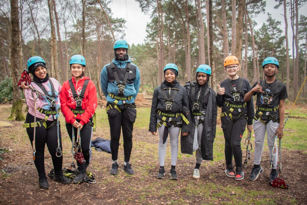 Youth Group with Youth Worker wearing harness and helmets in the forest ready to do zip wire