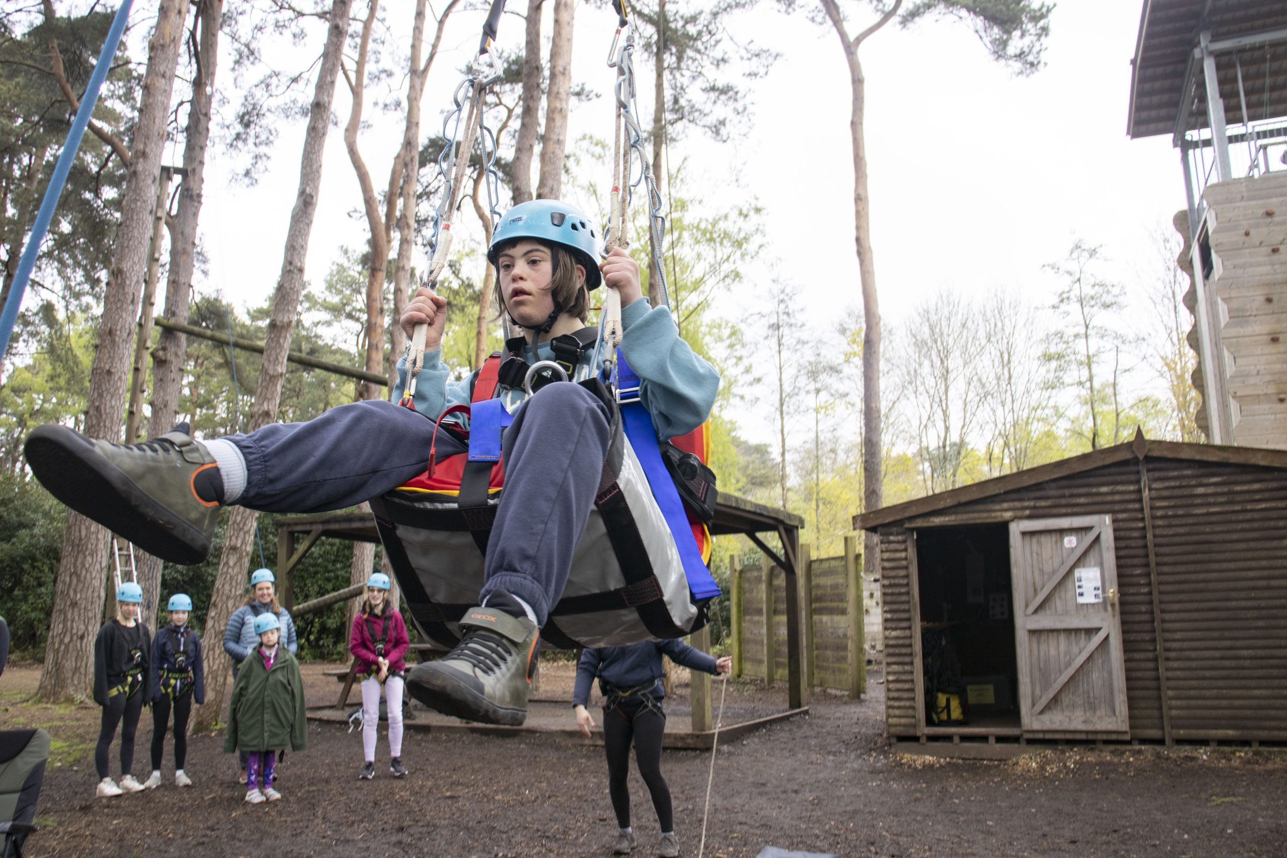 young person on a specialist hoist and harness doing high ropes in the new forest at Avon tyrrell
